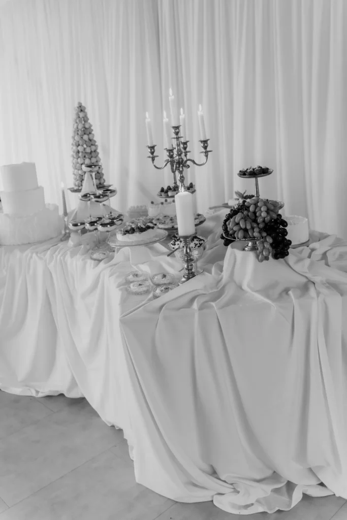Dekorirani buffet stol Cateringa Majetić s kolačima, voćem, tortama i svijećnjacima u elegantnom ambijentu.
