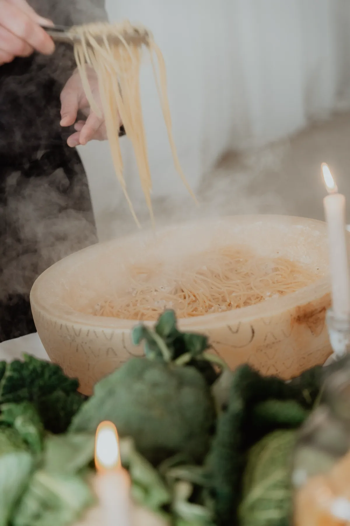 Kuhani špageti poslužuju se u izdubljenom kolutu parmezana, s parom koja se diže iz jela.